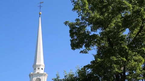 White Church Steeple with Blue Sky and Tree in Foreground Stock Footage