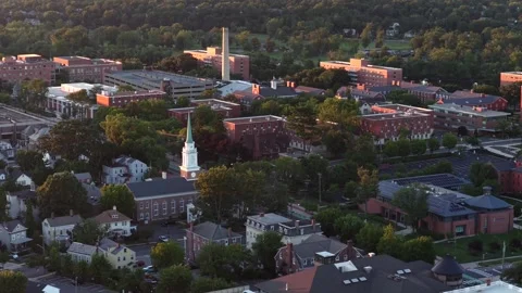 White church steeple with clock rises among red brick institutional buildings Stock Footage 340969509