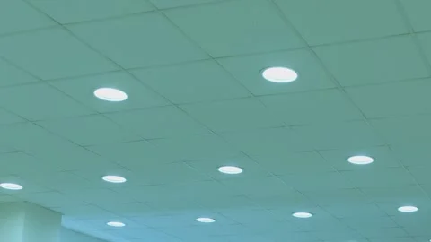 White circle lights turns on alternately on ceiling of dark , industrial room Video stock 195889556