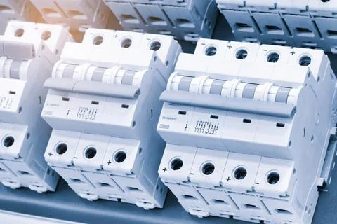 White circuit breakers with teal handles arranged neatly in rows. Blue tray s Stock Photos