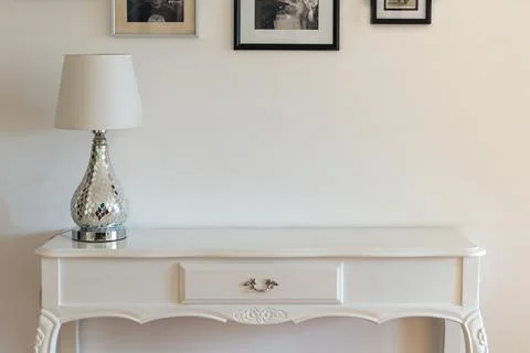 White classic console with a modern lamp on it Stock Photos