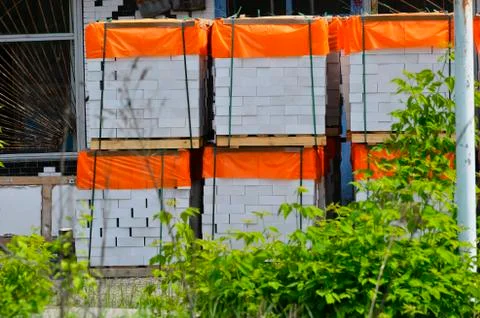 White clay bricks, stacked on pallets in an open warehouse Stock Photos