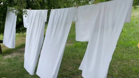 White clean bed sheets blowing in the wind on washing line in the garden Stock Footage 279065928