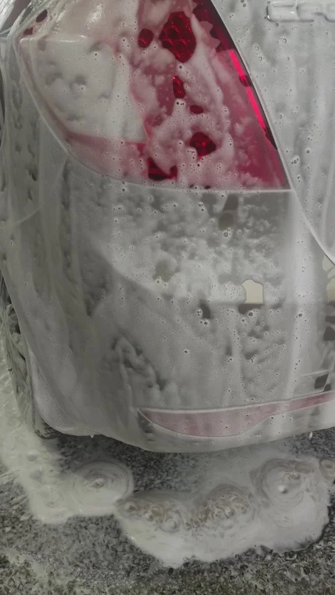 White cleaning foam dripping down rear car light and bumper Stock Footage 332921801