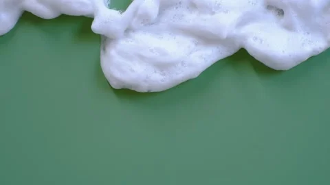White cleansing foam dripping on green background close-up. Stock Footage 294647851
