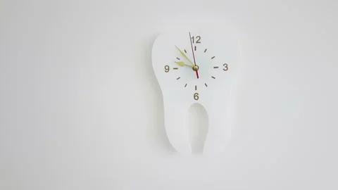 White clock in the form of a tooth on a light gray wall Stock Footage 154678260