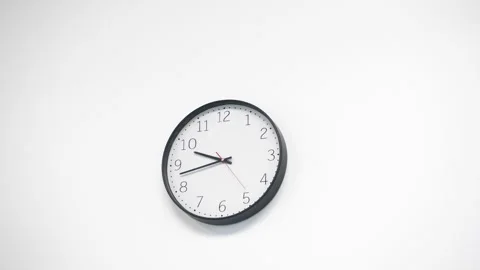 A white clock hangs on a white wall. The clock that goes by shows the exact time 스톡 동영상 198680733