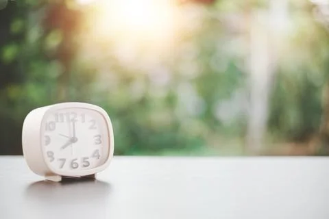 A white clock is placed on a wooden table, the concept of extinction of tim.. Stock Photos