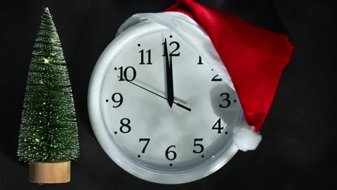 White clock in a santa hat next the Christmas tree. The second hand goes to 12 o Video stock 165915146