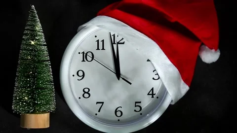 White clock in a santa hat next the Christmas tree. The second hand goes to 12 o Stock Footage 167241211