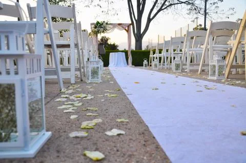 White cloth runner flanked by empty white chairs leading to a weeding altar Stock Photos