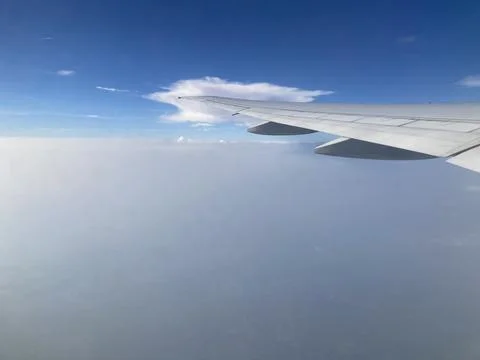 White cloud around the tip of the airplane wing and the smoke covering the town Stock Photos