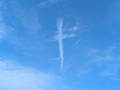 A white cloud in blue sky in the shape of a religious cross lines Stock Photos