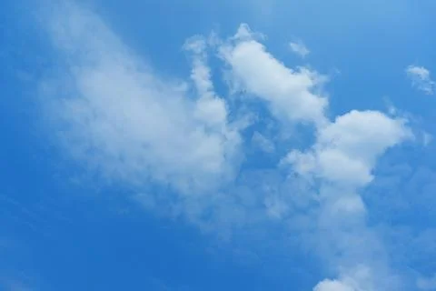 A white cloud breaking into smaller pieces against a blue sky. Diffusion and  Stock Photos