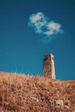 A white cloud hangs over the ancient stone tower Stock Photos