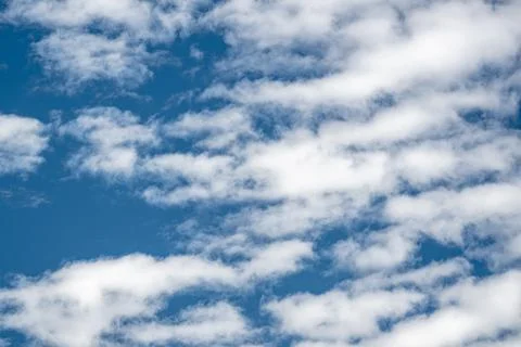 White cloud patterns drifting across a deep blue sky in clear daylight Stock Photos