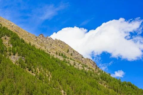 A white cloud seems to come out from the side of a mountain Stock Photos