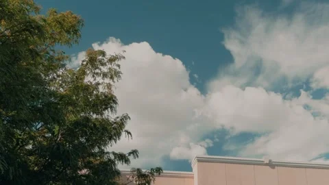 White Clouds in Blue Sky Above Tree and Building Roof Vídeos de archivo 345047676