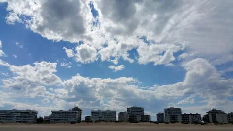 White clouds on the blue sky background over buildings on the seacoast Stock Photos