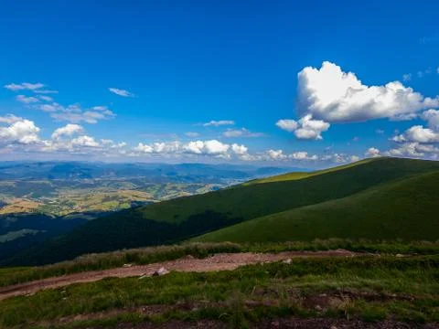 White clouds in the blue sky floating above the mountain peaks stretching to  Stock Photos