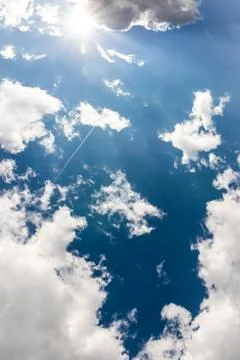 White Clouds Blue Sky Fluffy Sun Flare Airplane Trail  Sunny Daytime Texture  Stock Photos