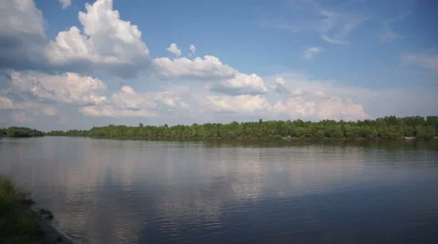 White clouds on the blue sky over the river with green banks. Timelapse. Stock Footage 67902338