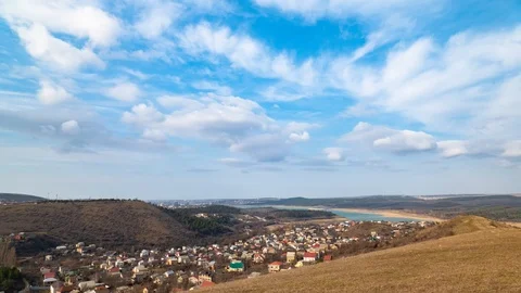 White clouds in blue sky over village in the valley between hills, time lapse Stock Footage 125451501