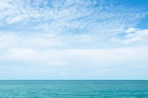 White clouds on blue sky over the calm ocean in sunny day. Stock Photos