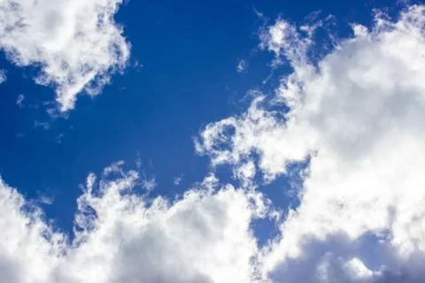 White clouds in the blue sky. The rays of the sun make their way through the  Stock Photos