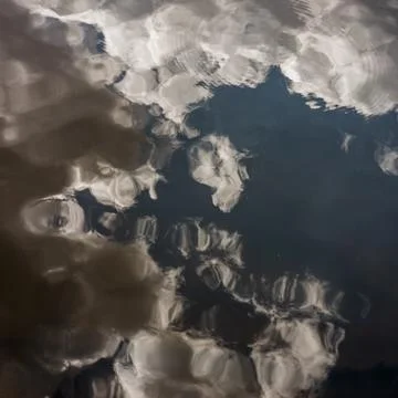 White clouds in the blue sky reflected in a lake in Auvergne, France Stock Photos