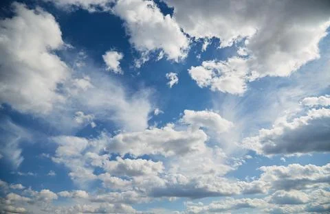 White clouds in the blue sky in sunlight, heavenly landscape with clouds to t Stock Photos