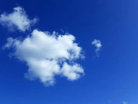 White Clouds in Clear Blue Sky. A puffy cumulus cloud. Calm cloudscape. Stock Photos