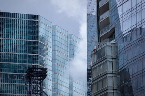 White clouds crawling between glassy walls of skyscrapers Stock Photos