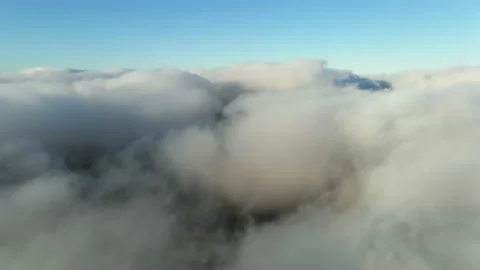 White clouds of dense fog move quickly over sea and coastline blue sky Stock Footage 142954917