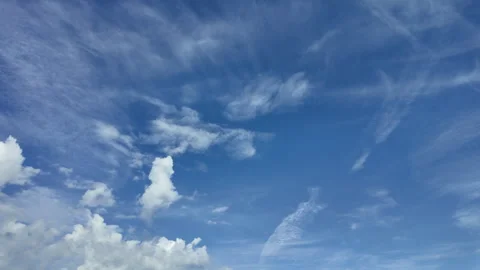 White clouds drifting and transforming across a vivid blue summer sky, creating Stock Footage 346049351