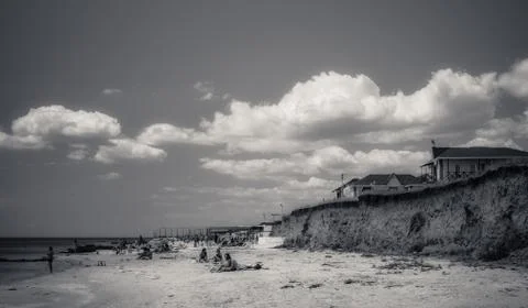 White clouds float across the blue sky above the sea Stock Photos
