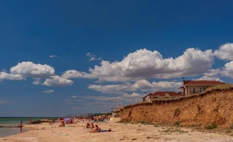 White clouds float across the blue sky above the sea Stock Photos