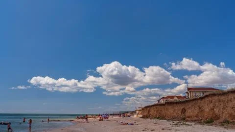 White clouds float across the blue sky above the sea Stock Photos