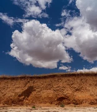 White clouds float across the blue sky over the cliff Stock Photos