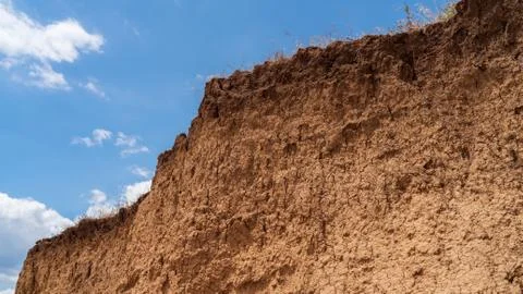 White clouds float across the blue sky over the cliff Stock Photos