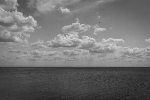 White clouds float across the blue sky above the sea Stock Photos