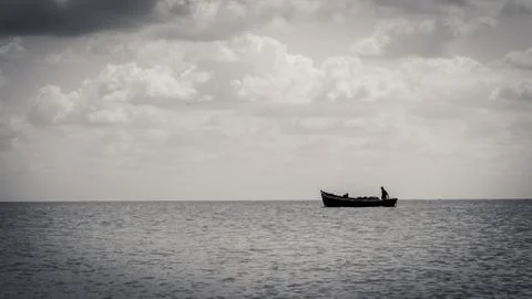White clouds float across the blue sky above the sea Stock Photos