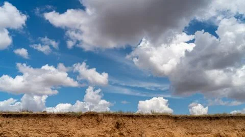 White clouds float across the blue sky over the cliff Stock Photos