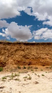 White clouds float across the blue sky over the cliff Stock Photos