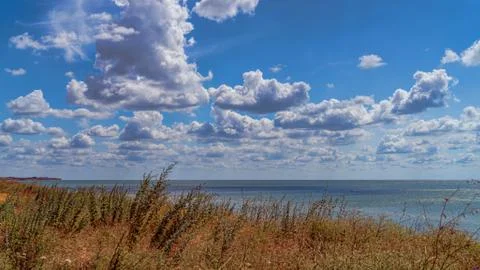 White clouds float across the blue sky over the cliff Stock Photos