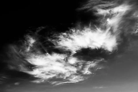 White clouds float against a dark black sky in this high contrast monochrome Stock Photos