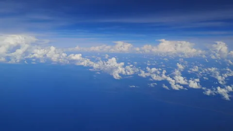 White clouds float gently over the ocean and coastline seen from the window. Stock Footage 318795527