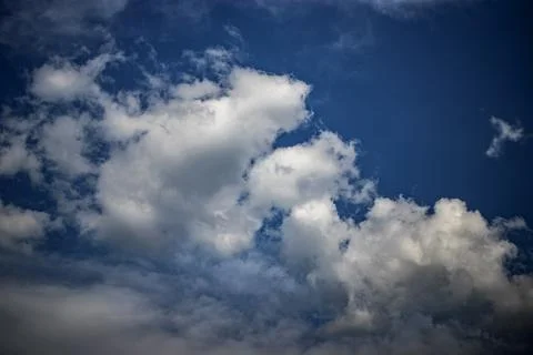 White clouds float lazily in a deep blue sky, casting soft shadows on the lan 스톡 사진