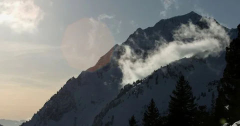 White clouds floating near the snow covered mountain during sunset Stock Footage 77765283