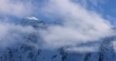 White clouds floating over the snow-covered mountain ranges during winter Stock Footage 77766654